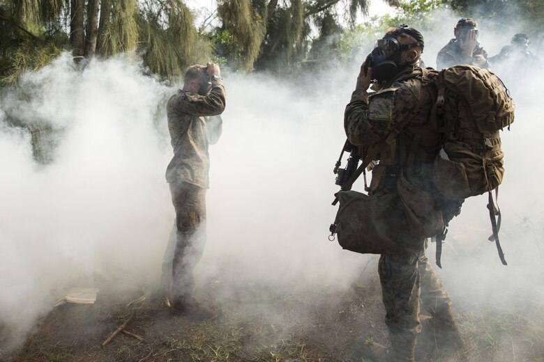 KAHUKU TRAINING FACILITY – Marines don their gas masks as simulated hostiles use O-chlorobenzalmalononitrile gas (CS gas) during a raid as part of a training exercise aboard the Kahuku Training Facility, Sept. 20, 2016. The exercise is part of a 7-week-long training known as the Advance Infantry Course. The Advance Infantry Course, which is conducted by the Advance Infantry Battalion, Detachment Hawaii, is an advanced 0311 (Rifleman) Military Occupational Specialty course for squad leaders who are currently serving in the operating field. Originally only for 3rd Marine Division, the course here has opened up to various infantry units throughout the Marine Corps. Marines start with a week of proofing their prerequisites that are required for the course, confirming their basic skill sets, and then spend two weeks in a garrison environment doing course work and physical training routines geared toward the squad leader. Towards the second half of the course, Marines conduct one live fire week, followed by three consecutive weeks in the field, progressing from an urban exercise to a patrolling exercise, with offensive and defensive tactics. Marines trained in multiple areas on the island, from high in the mountains of the Kahuku Training Facility to the Military Operation in Urban Terrain facilities on Marine Corps Training Area Bellows. (U.S. Marine Corps Photo by Lance Cpl. Jesus Sepulveda Torres)
