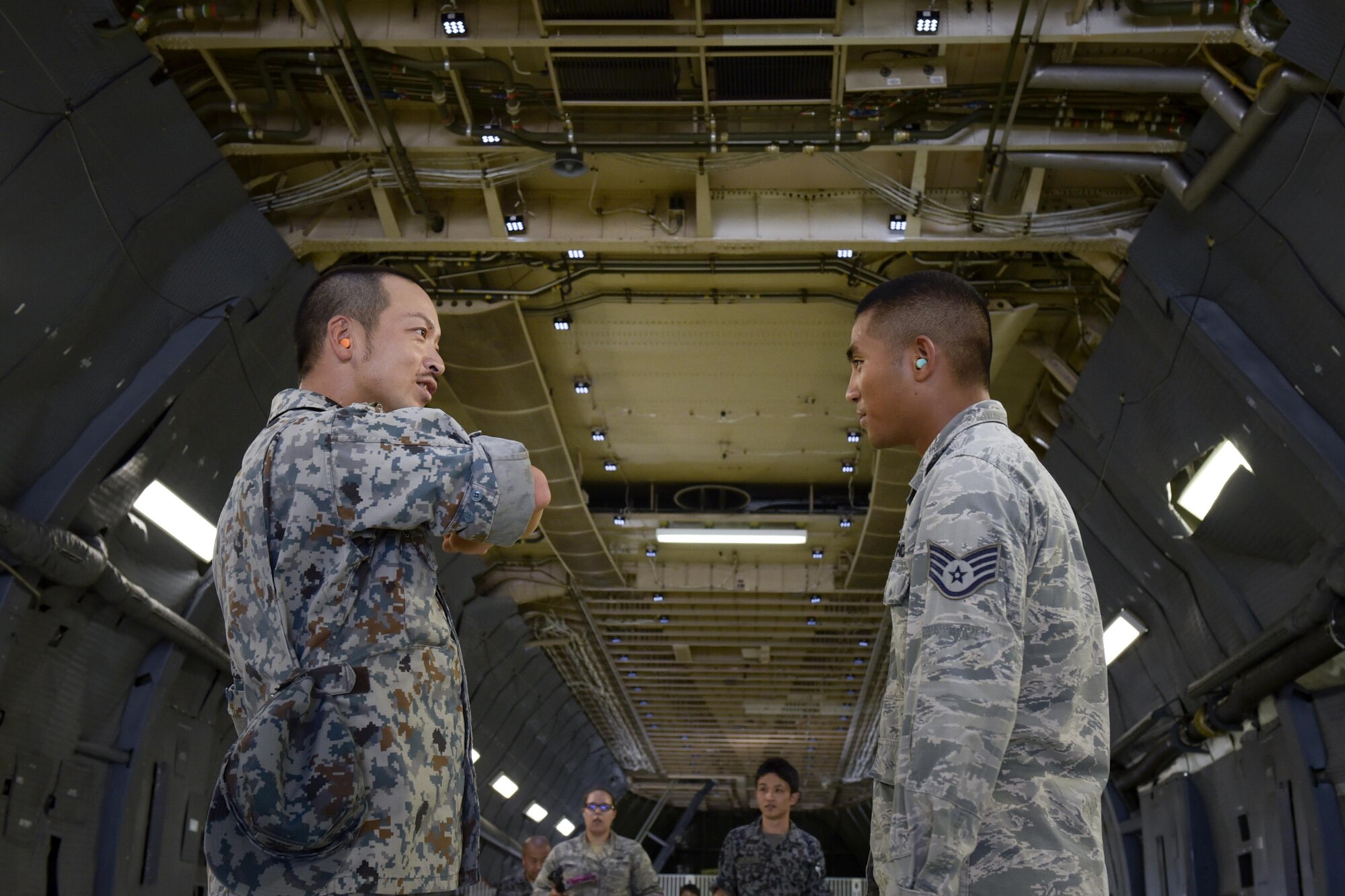 Japan Air Self-Defense Force Tech. Sgt. Kazuhiro Shiraishi, 3rd Operation Squadron civil engineer, talks with U.S. Air Force Staff Sgt. Jon Mark Quibar, 374th Civil Engineer Squadron service contract supervisor, inside of a C-5M Super Galaxy during the Bilateral Exchange Program at Yokota Air Base, Japan, Sept. 27, 2016. Members of the JASDF toured base dormitories, a C-5M Super Galaxy aircraft and the 374th Security Forces Squadron K-9 facility. (U.S. Air Force photo by Machiko Imai/Released)