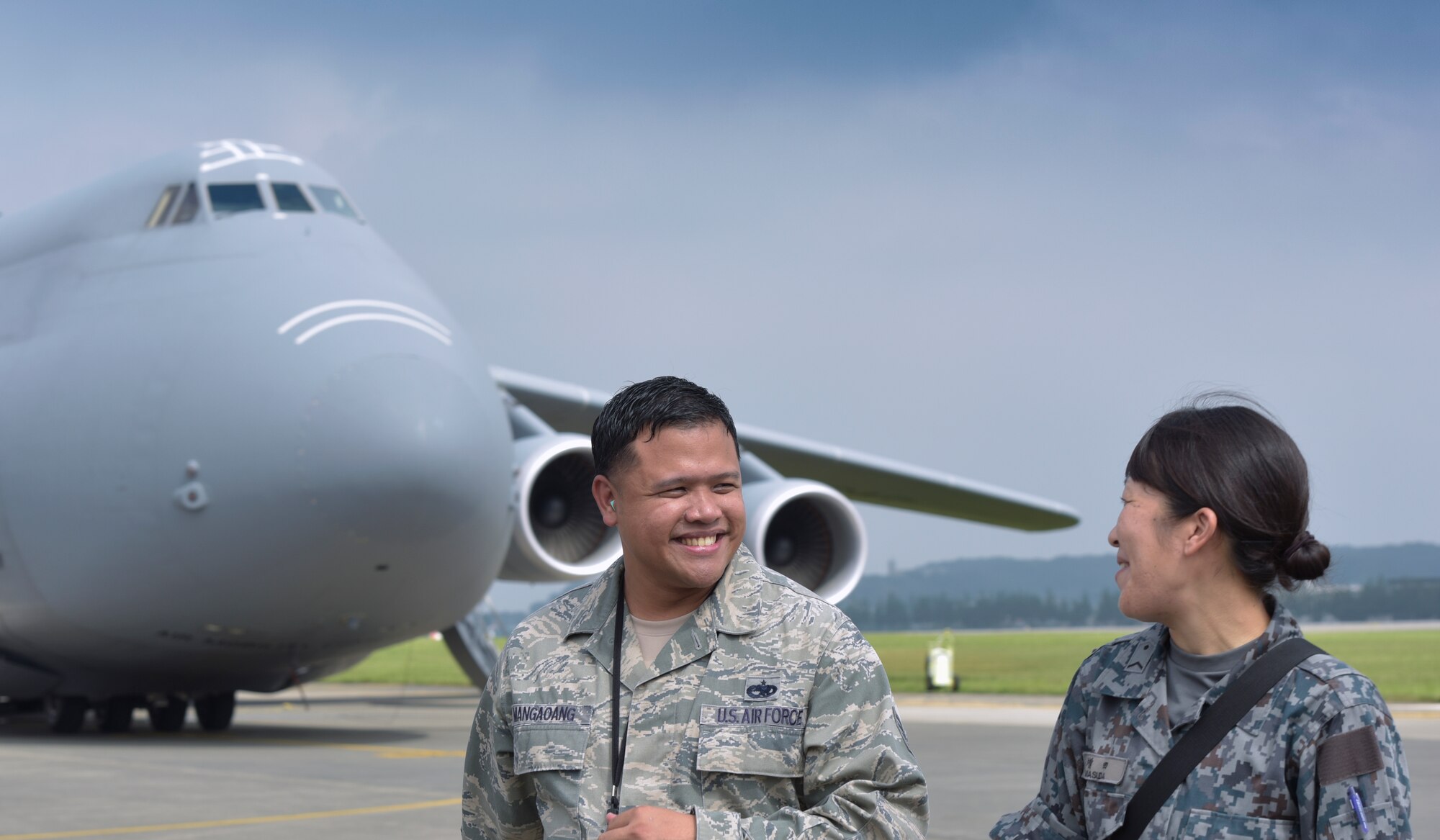 U.S. Air Force Tech. Sgt. Mangaoang Mike, 730 Air Mobility Squadron quality assurance lead inspector, talks with Japan Air Self-Defense Force Staff. Sgt. Megumu Masuda, 1st Tactical Airlift Wing integrated communications countermeasures and navigation systems technician, during the Bilateral Exchange Program at Yokota Air Base, Japan, Sept. 27, 2016. Members of the JASDF toured base dormitories, a C-5M Super Galaxy aircraft and the 374th Security Forces Squadron K-9 facility. (U.S. Air Force photo by Machiko Imai/Released)