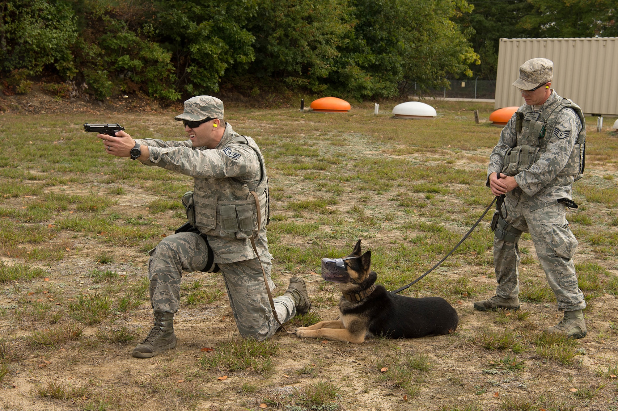Staff Sgt. David Schultz, 66th Security Forces Squadron Military Working Dog handler, fires his M9 pistol during live fire training at Fort Devens, Mass., Sept. 27, while Staff Sgt. Adam Dunnam, 66th SFS MWD handler, and MWD Peta, watch nearby. Members of the security forces participated in the live fire training with their military working dog counterparts. (U.S. Air Force photo by Jerry Saslav)
