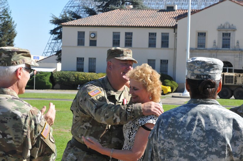 Maj. Gen. Nickolas Tooliatos smiles as he hugs his wife Joni during a retirement ceremony, Sept. 25, Moffett Field, Mountain View, Calif. Tooliatos, retired after 36 years of service to the Army Reserve after relinquishing command of the 63rd Regional Support Command. (U.S. Army Reserve Photo by Capt. Alun Thomas)