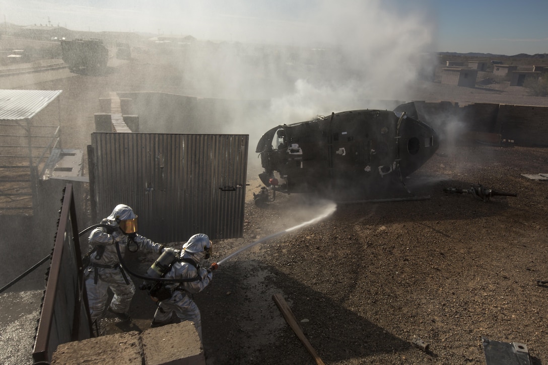 U.S. Marine Corps Sgt. Adrian Rosas, left, and Cpl. Thomas Ream, aircraft rescue and fire fighter specialists with Marine Wing Support Squadron 372, douse a downed aircraft during an aircraft salvage practical application exercise in support of Weapons and Tactics Instructor Course (WTI) 1-17 at Yuma Proving Ground, Ariz., Sept. 28, 2016. This exercise was part of WTI 1-17, a seven week training event, hosted by Marine Aviation Weapons and Tactics Squadron One (MAWTS-1) cadre, which emphasizes operational integration of the six functions of Marine Corps aviation in support of a Marine Air Ground Task Force. MAWTS-1 provides standardized advanced tactical training and certification of unit instructor qualifications to support Marine Aviation Training and Readiness and assists in developing and employing aviation weapons and tactics.