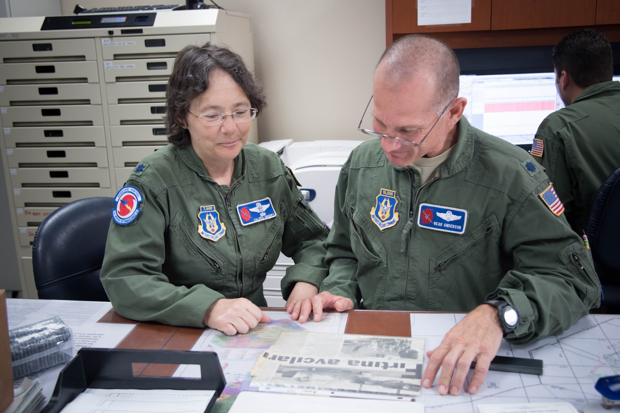 Lt. Col. Troy “Bear” Anderson, 53rd Weather Reconnaissance Squadron pilot and Lt. Col. Valerie Hendry 53rd WRS aerial reconnaissance weather officer, look at an old newspaper clipping before the final flight of their Air Force careers. (U.S. Air Force photo/Senior Airman Heather Heiney) 