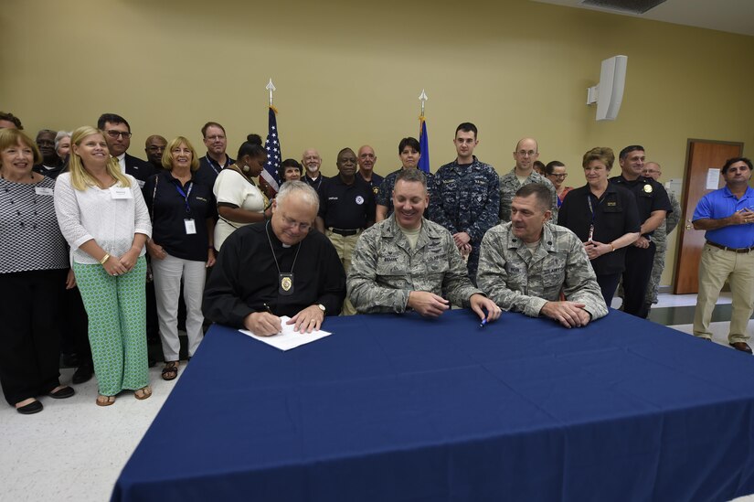 Rev. Rob Duey, Coastal Crisis Chaplaincy chaplain (left), Col. Robert Lyman, 628th Air Base Wing commander (center), and Lt. Col. Walter Bean, 628th ABW chaplain sign a Memorandum of Agreement here Sept. 21, 2016.  The MOA establishes written guidelines between the Joint Base Chaplain's office and the Coastal Crisis Chaplaincy.  This organization provides emergency, crisis intervention and counseling services to local EMS, first responders and other local agencies.  The Coastal Crisis Chaplaincy will collaborate with the JB Charleston Chaplain’s office as part of the chapel’s P4 initiatives. The program establishes local partnerships and bolsters networking and communications between religious officials across the Lowcountry. 