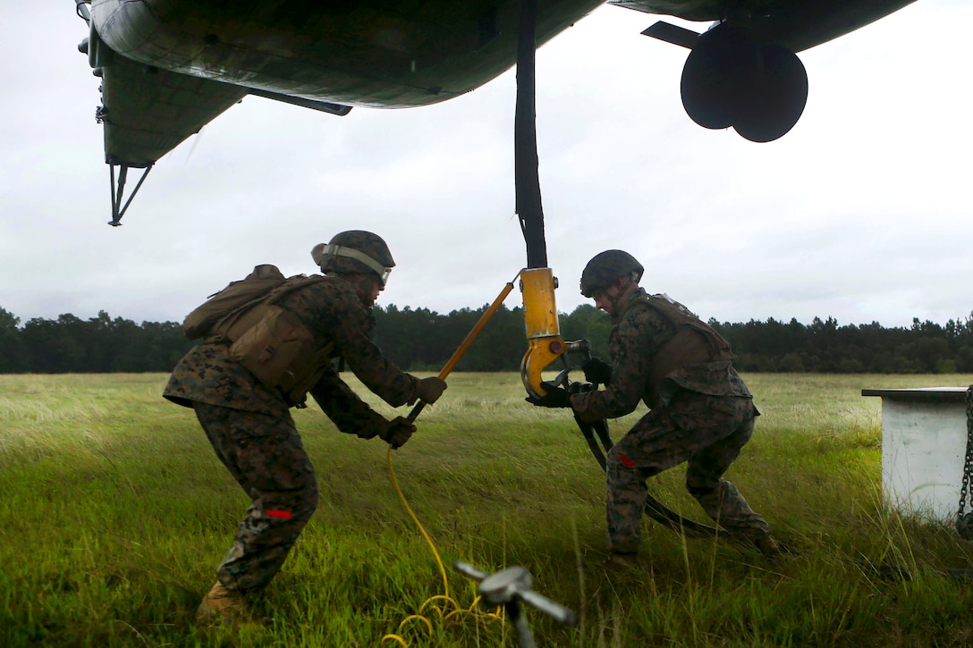 Marine Corps Lance Cpl. Keaton Grey, right, and Pfc. Marine Corps David Laube attach the load hook to a CH-53 Sea Stallion during  hoist training at Camp Lejeune, N.C., Sept. 20, 2016. Grey and Laube are assigned to Combat Logistics Battalion 26, Headquarters Regiment, 2nd Marine Logistics Group. Marine Corps photo by Lance Cpl. Jack A. E. Rigsby