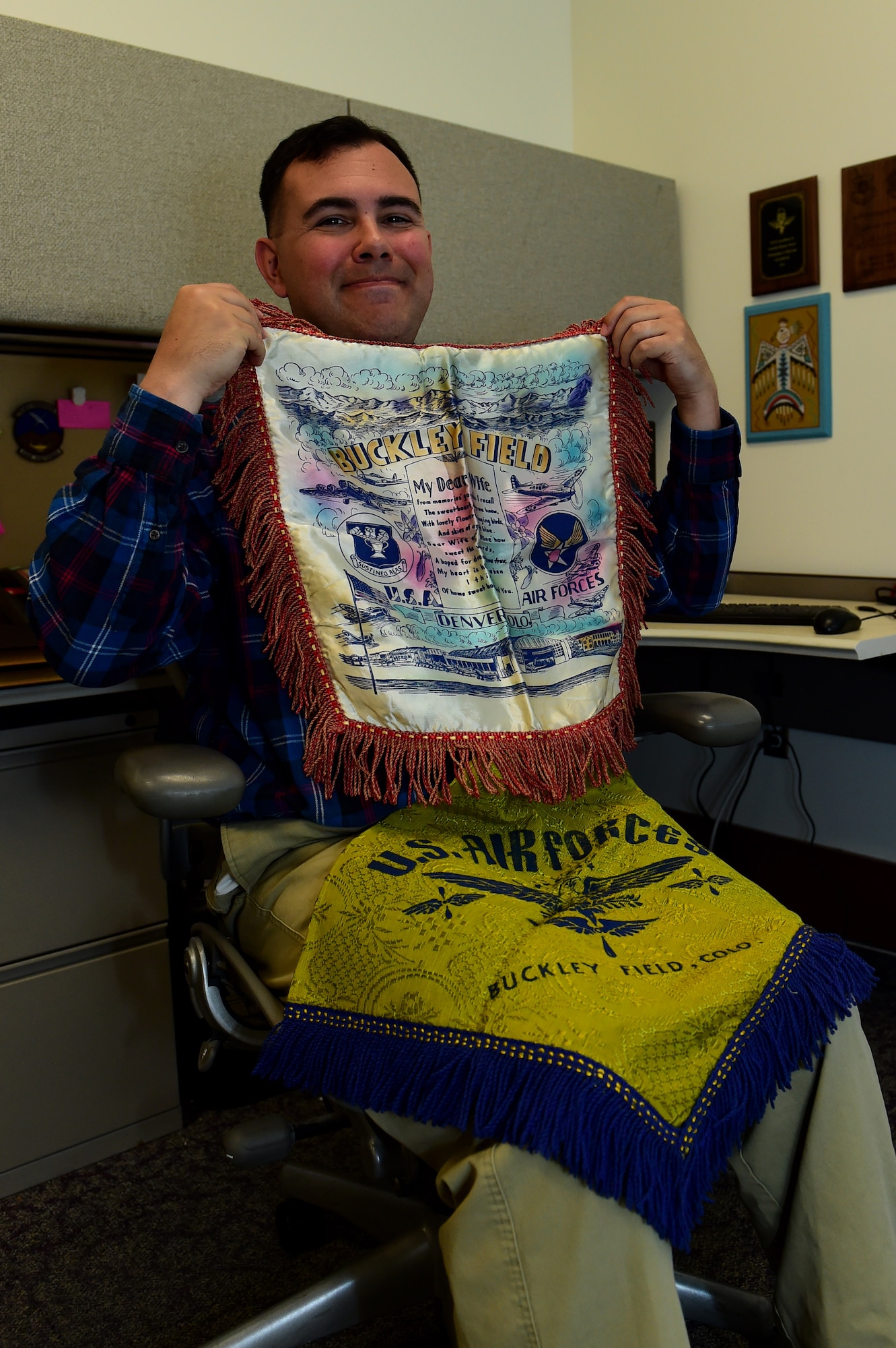 Christopher McCune, 460th Space Wing historian, displays a blanket and pillow cover from Buckley Air Force Base’s past Sept. 26, 2016, at the 460th Space Wing Headquarters building on Buckley AFB, Colo. U.S. Air Force Historians, like McCune, are responsible for maintaining historic artifacts, such as newspapers. (U.S. Air Force photo by Airman 1st Class Gabrielle Spradling/Released)
