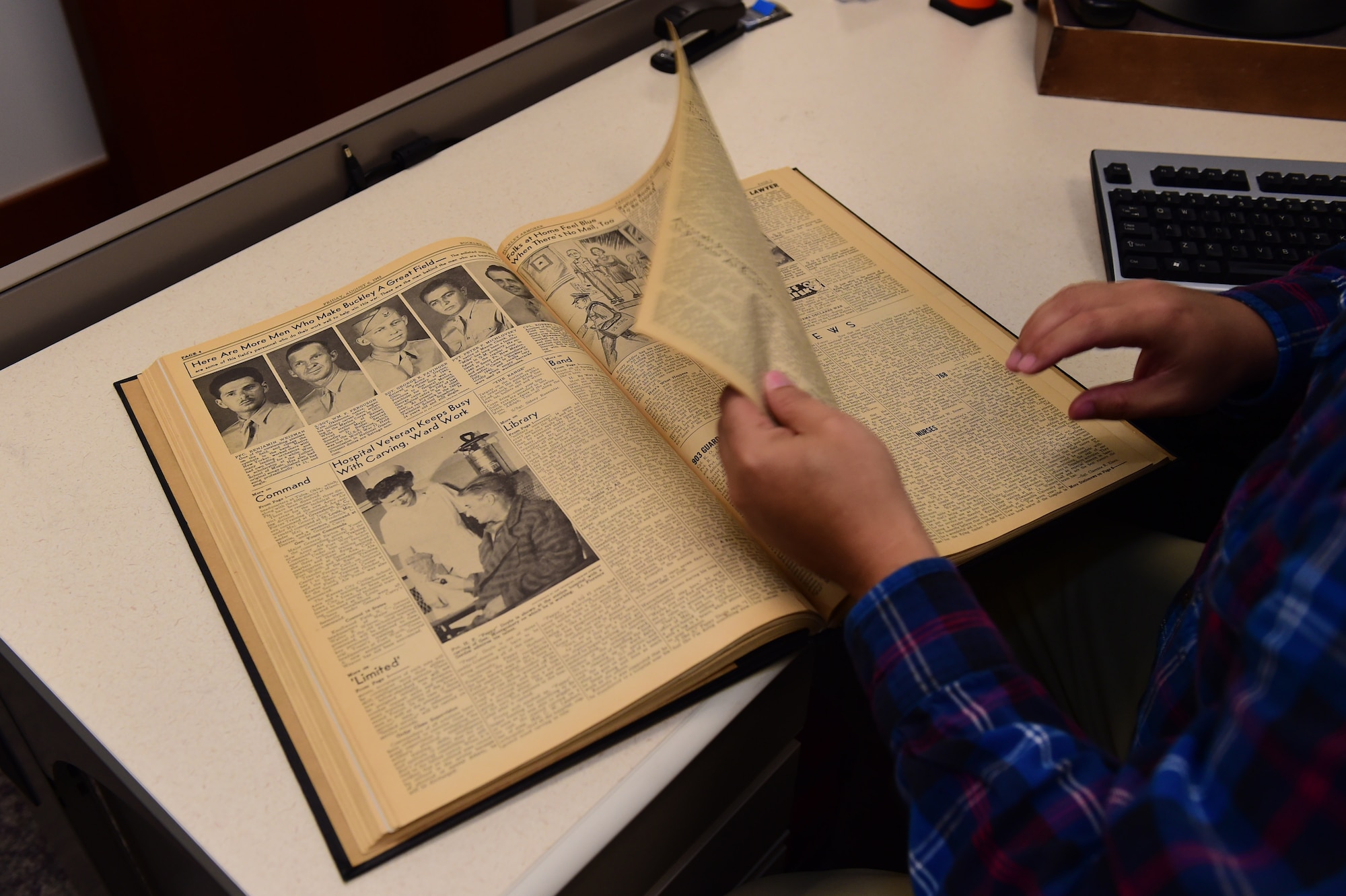 Christopher McCune, 460th Space Wing historian, turns a page in a book documenting the 1943 Buckley newspaper editions Sept. 26, 2016, at the 460th Space Wing Headquarters building on Buckley Air Force Base, Colo. A historian’s core responsibility is documenting and sustaining the heritage of Air Force organizations. (U.S. Air Force photo by Airman 1st Class Gabrielle Spradling/Released)