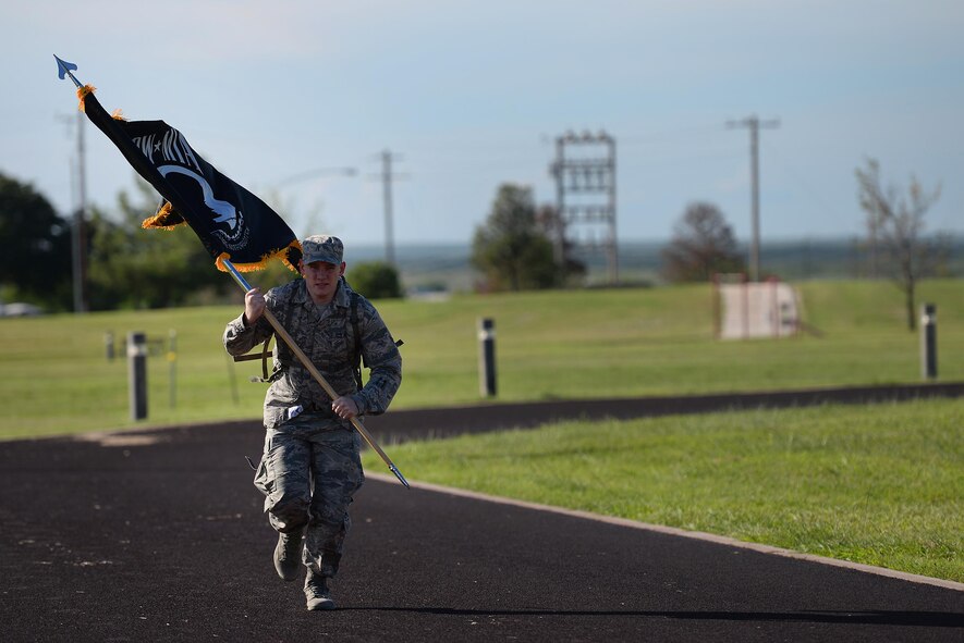 Airman 1st Class Hunter Auvil, 47th Operation Support Squadron flight records assistant, sprints a lap with the Prisoners of War/Missing in Action flag during a 24-hour ruck march on Laughlin Air Force Base, Texas, Sept. 15, 2016. Equipped with a ruck sack filled with sandbags, Auvil ran to honor of those who were captured or went missing during battle. (U.S. Air Force photo/ Airman 1st Class Benjamin N. Valmoja)