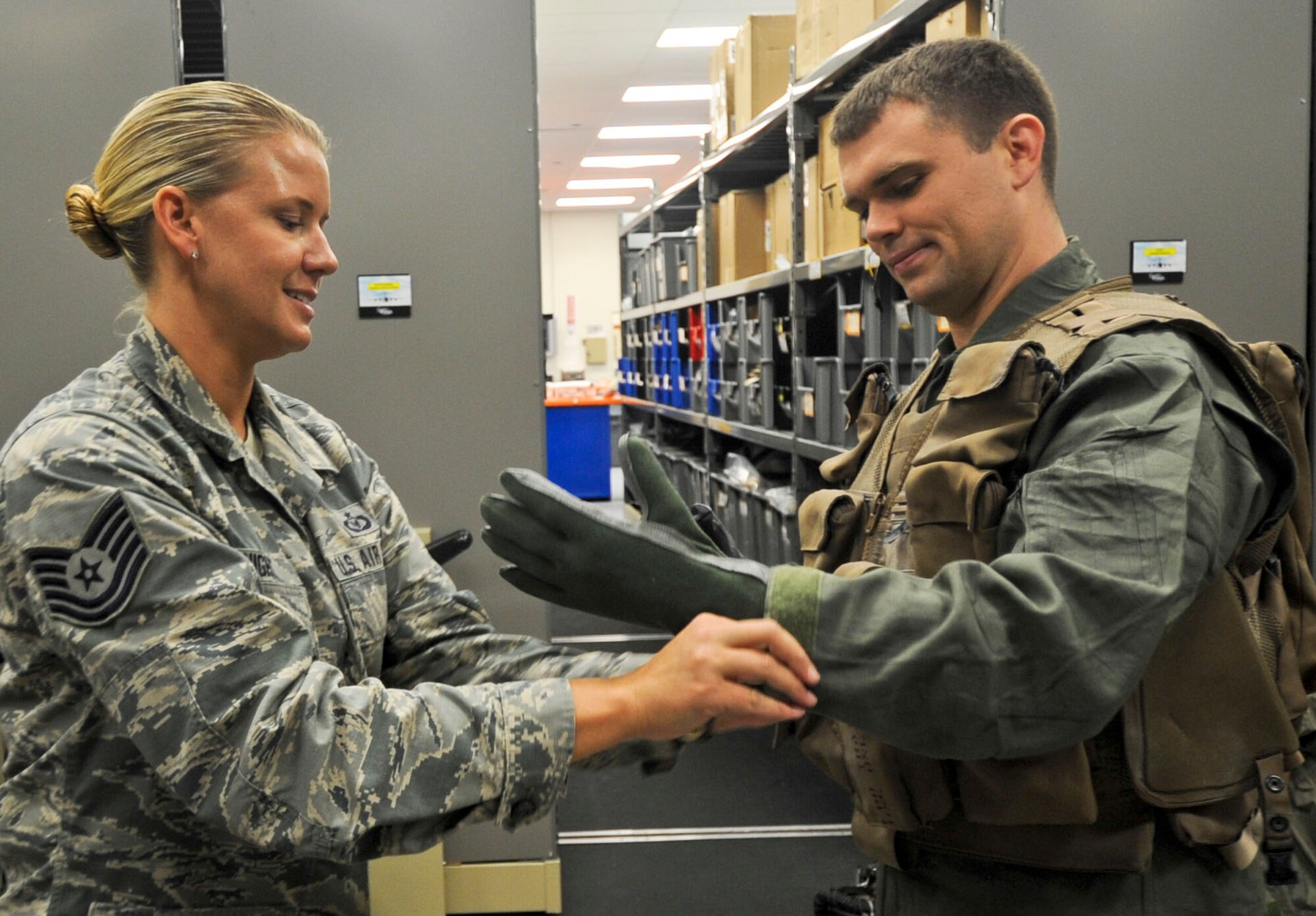 Tech. Sgt. Lindy Knight, 1st Special Operations Support Squadron, assists 1st Lt. Robert Dolin, 535th Airlift Squadron C-17 pilot, with putting on protective gloves in preparation for processing through an Aircrew Contamination Control Area (ACCA) as part of Exercise Toxic Pineapple on Joint Base Pearl Harbor-Hickam, Hawaii, Sept. 16, 2016. The purpose of the ACCA is to establish a location to provide detection, contamination control and processing provisions for aircrew members into a toxic free environment. (U.S. Air Force photo by Tech. Sgt. Terri Paden/Released)