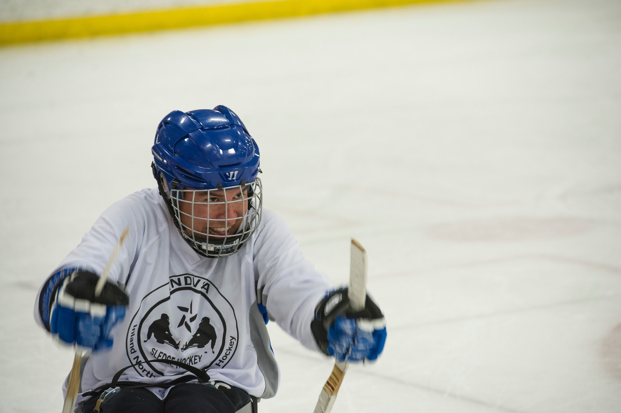 Master Sgt. Richard Ortega, Fairchild Falcons varsity hockey team president, races toward a puck during the exhibition sled hockey match at the Frontier Ice Arena here in Coeur d’Alene, Idaho, Sept. 23, 2016. Instead of ice skates on their feet, sled hockey athletes are outfitted with sleds and short hockey sticks with metal “teeth.” The teeth allow for traction on the ice and propels the players in the direction of their choice. (U.S. Air Force photo/Tech. Sgt. Travis Edwards)
