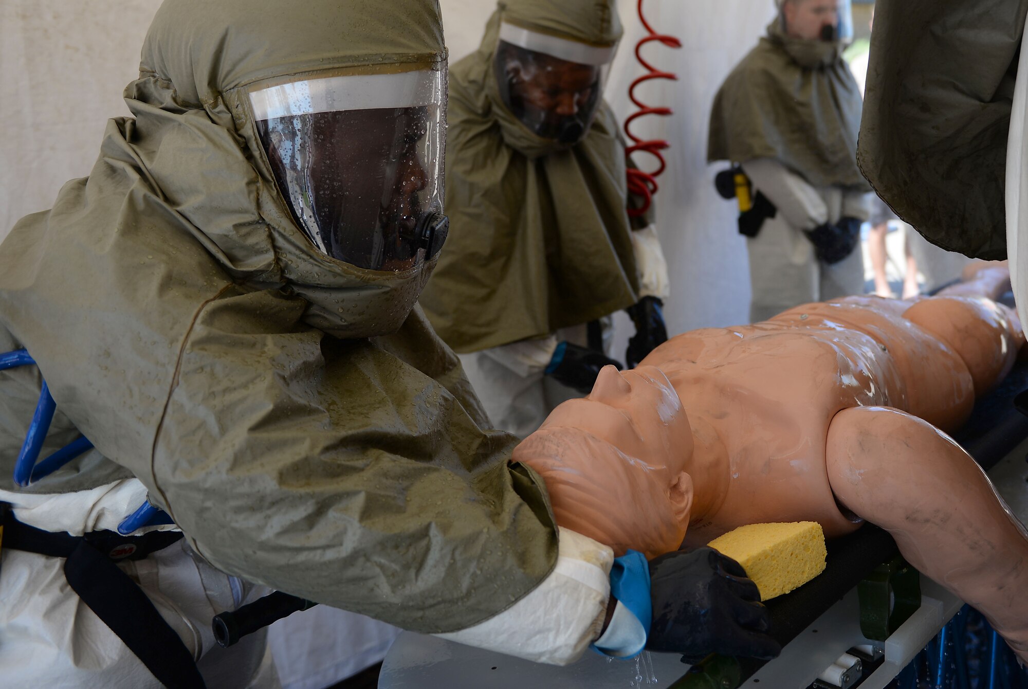 Senior Airman Johnathan Gwei (left), 47th Medical Support Squadron referral management technician, wipes down a simulated patient during a decontamination training course on Laughlin Air Force Base, Texas, Sept. 22, 2016. During the exercise, a team of 18 practiced putting up a mobile decontamination center, treating patients, then tearing it down. (U.S. Air Force photo/Airman 1st Class Benjamin N. Valmoja)