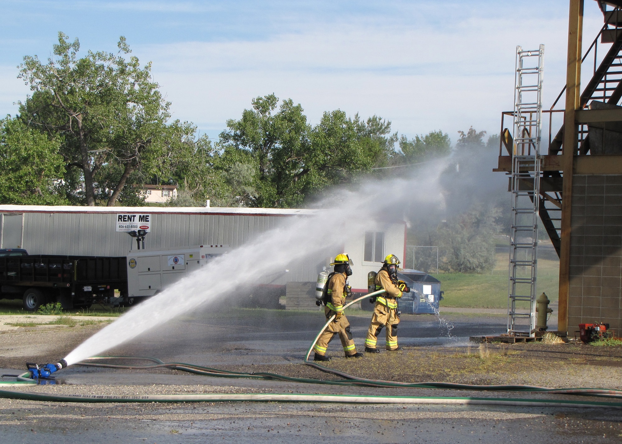 Two firefighters assigned to the 120th Fire and Emergency Services Flight operate a fire hose during training. The Montana Air National Guard firefighters conducted training with the city of Great Falls firefighters at the Charles C. Carrico Regional Training Facility in Great Falls, Mont., Aug. 15-30, 2016. (Photo courtesy 120th Fire and Emergency Services Flight)