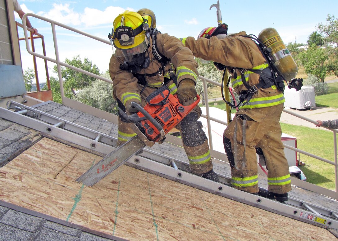120th Fire and Emergency Services Flight firefighters Staff Sgt. Olin McCrumb and Master Sgt. Ron Martin ventilate a roof over a training fire. The Montana Air National Guard firefighters conducted joint training with the city of Great Falls firefighters at the Charles C. Carrico Regional Training Facility in Great Falls, Mont., Aug. 15-30, 2016. (Photo courtesy 120th Fire and Emergency Services Flight)