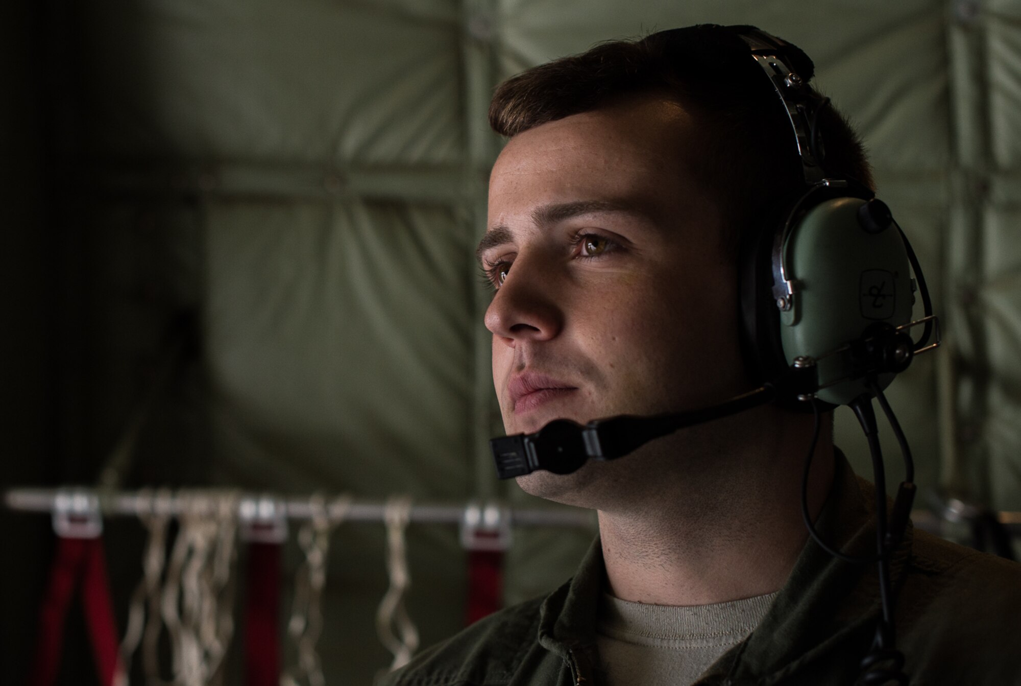 Senior Airman Anthony Oldham, 37th Airlift Squadron loadmaster, listens to communications from the cockpit while flying aboard a C-130J Hercules over the skies of Germany, Sept. 21, 2016. Oldham used some of the lessons his father, a retired Air Force Survival, Evasion, Resistance, and Escape instructor, taught him to save a civilian’s life while on temporary assignment to Poland, Oct. 17, 2015. (U.S. Air Force photo by Senior Airman Nesha Humes)