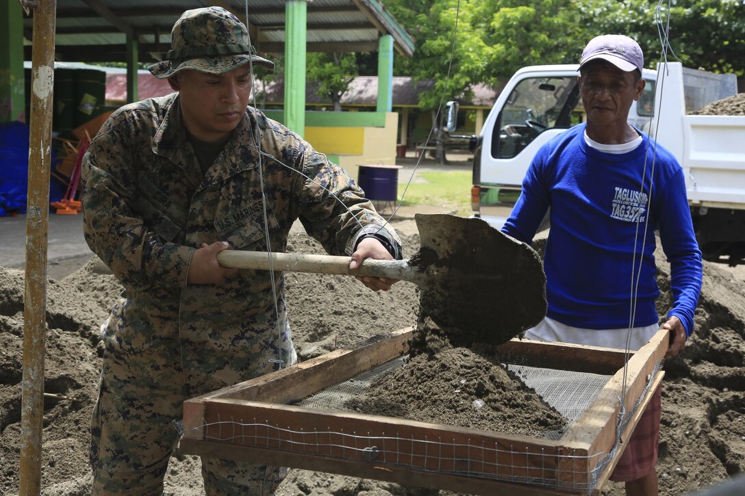 U.S. Marine Gunnery Sgt. Miguel Cira, a platoon sergeant with 9th Engineer Support Battalion, 3d Marine Logistics Group, shovels dirt into a filter with a local Filipino during a engineering civic assistance project for Philippine Amphibious Landing Exercise 33 (PHIBLEX) Sept 23, 2016. PHIBLEX 33 is an annual U.S.-Philippine military bilateral exercise that combines amphibious landing and live-fire training with humanitarian civic assistance efforts to strengthen interoperability and working relationships. (U.S. Marine Corps photo by MCIPAC Combat Camera Cpl. Allison Lotz/Released)