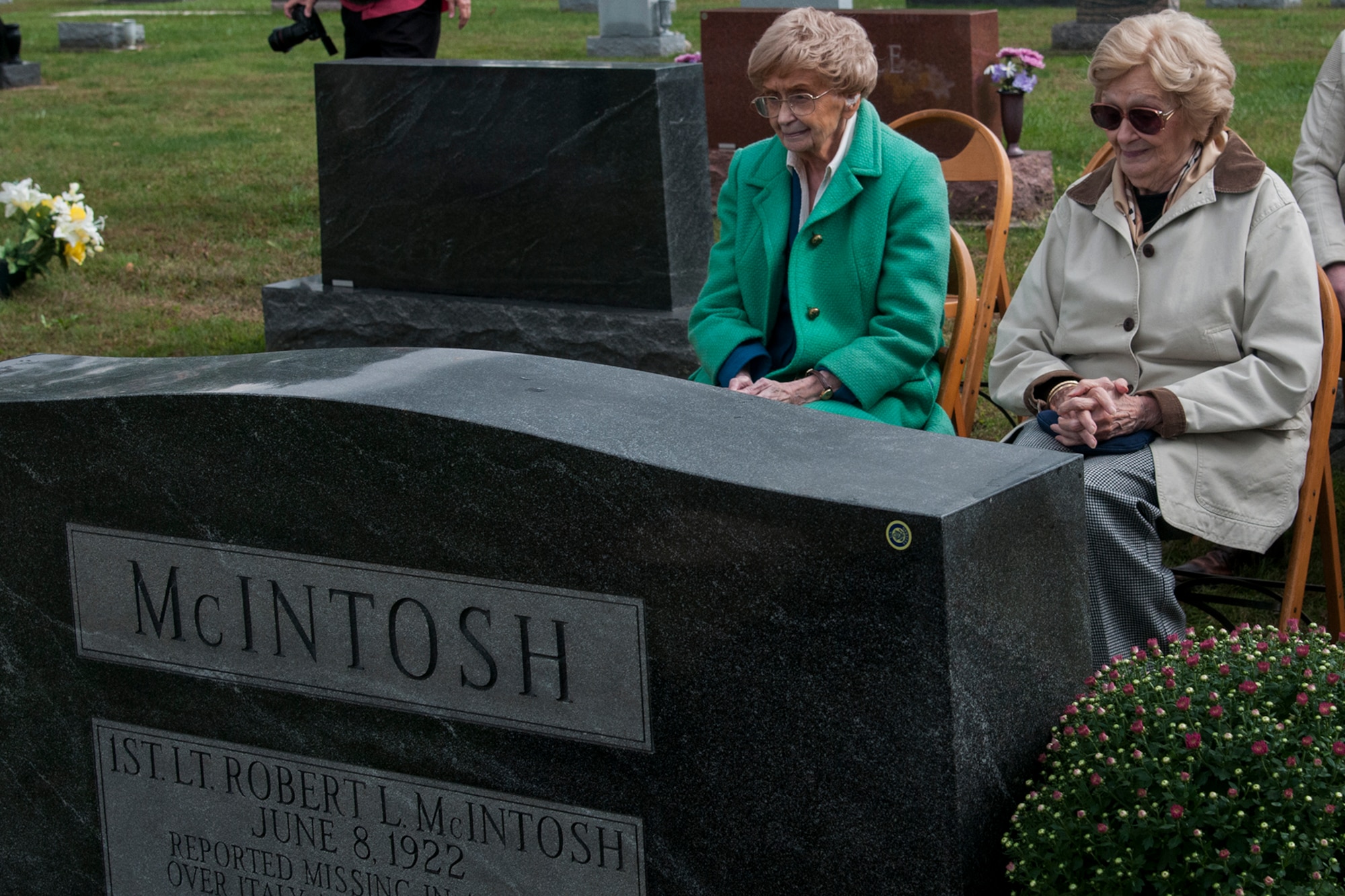 Patricia Talley and Jeannine Baker-McIntosh, sisters of Army Air Corps Lt. Robert McIntosh, 27th Fighter Squadron pilot, sit in front of their brother’s tombstone before a flyover Sept. 29, 2016 in Tipton, Ind. McIntosh’s aircraft crashed in 1942 and his remains were recently returned home. (U.S. Air Force photo/Staff Sgt. Dakota Bergl) 