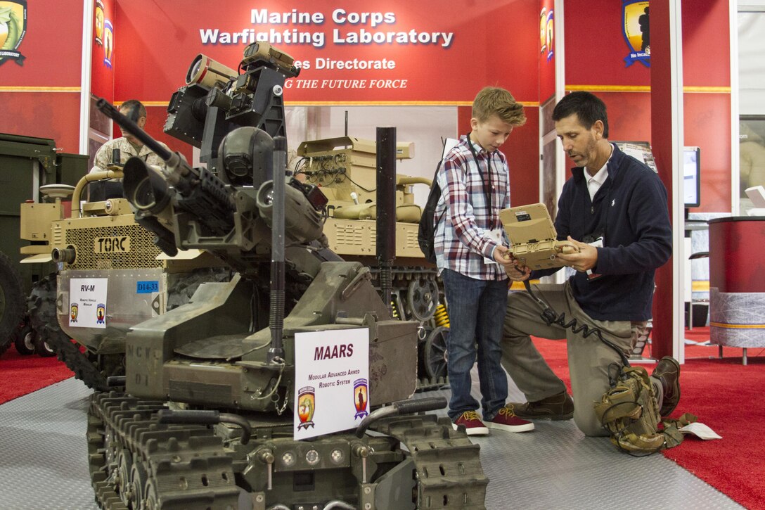 Brent Azzarelli shows Micah Daily how to operate the Modular Advanced Armed Robotic System during the Modern Day Marine Military Exposition (MDMME) held aboard Marine Corps Base Quantico, Va., Sept. 28, 2016. Micah drew a robot and wrote a note that said, “if you take me to the place ware you make all the Robots and stuff I will tell you how to build it," and sent it to Marine Corps Recruiting Command aboard MCB Quantico. Capt. David P. Foley read this letter and hand-delivered an invitation to Micah for the MDMME. Azzarelli is a contractor for Marine Corps Warfighting Lab. Foley is the adjutant officer for MCRC.