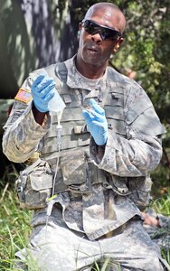 Sgt. 1st Class Antoine J. Brisson prepares to give a wounded Soldier an intravenous saline line during the U.S. Army Medical Department Center & School 2016 Best Medic competition at Camp Bullis Sept. 12-14. 
