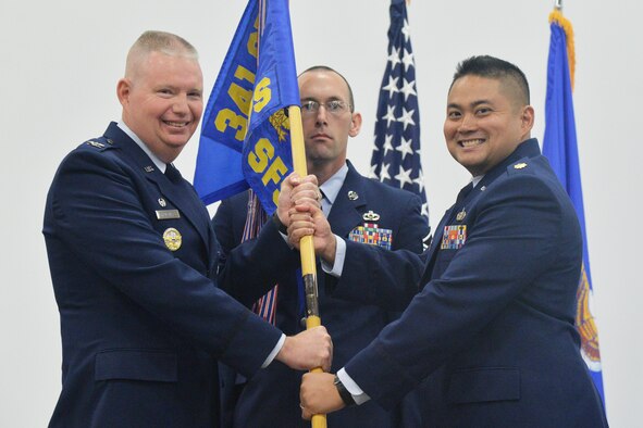 Maj. Marc Ortiz, right, accepts command of the 341st Security Forces Squadron from Col. Robert Frederiksen, 341st Security Forces Group commander, during a change of command ceremony at the Grizzly Bend Sept. 30, 2016. Master Sgt. Jeffery House, 341st SFS first sergeant, looks on. (U.S. Air Force photo/Airman 1st Class Daniel Brosam)