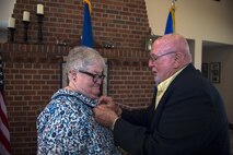 John, husband of Ann Lukens, 23d Force Support Squadron school liaison officer, places a retirement pin on his wife during her retirement ceremony, Sept. 30, 2016, at Moody Air Force Base, Ga. The native New Yorker enlisted in the Air Force in 1976 and married then Staff Sgt. John Lukens. Ann served from 1976-1979 at Peterson AFB, Colorado, separating afterwards. Since then, she has accompanied John to bases located in Minnesota, Greece, Florida and Georgia. (U.S. Air Force photo by Airman 1st Class Greg Nash)