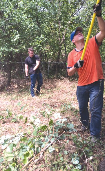 Staff Sgt. Bryan Lemire, front, works on a tree while Tech. Sgt. Josh Simmons clears yard debris during a volunteer clean-up day at the home of injured co-worker Staff Sgt. Fred Gilmore. About two dozen volunteers showed up Aug. 20 to help Sergeant Gilmore’s family. (Courtesy photo)
