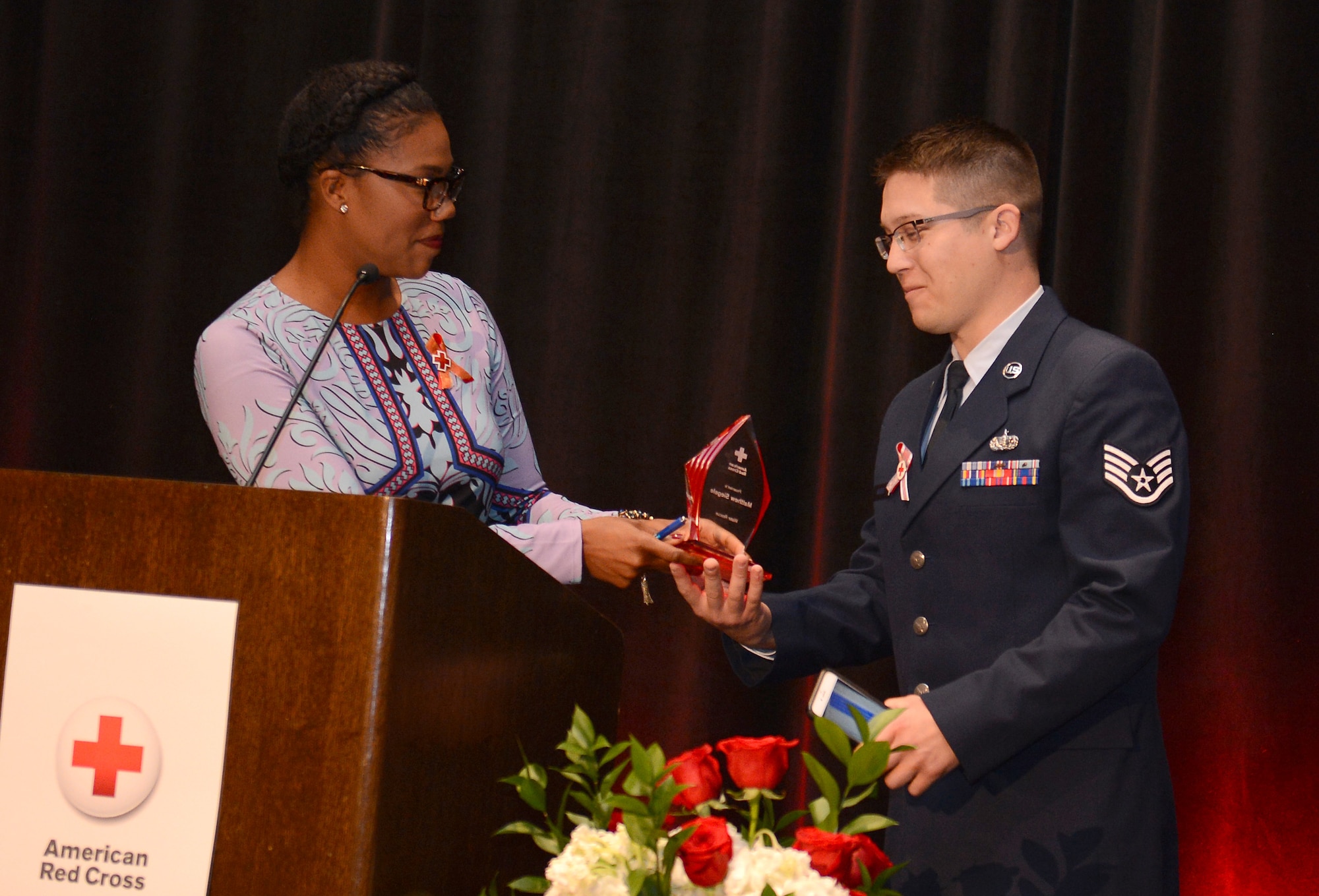 Jenna Hanchard (left), host and reporter from KING 5 TV station, presents the 2016 American Red Cross Water Rescue Hero Award to Staff Sgt. Matthew Siegele (right), 627th Force Support Squadron sports and fitness NCO in charge, during the American Red Cross 2016 Heroes luncheon Sept. 28, 2016 in Tacoma, Wash. Siegele received the 2016 Water Rescue Hero Award for the heroic act he performed on Jan. 1 when a little girl fell through the ice on Carter Lake at Joint Base Lewis-McChord, Wash. (U.S. Air Force photo/Senior Airman Divine Cox)