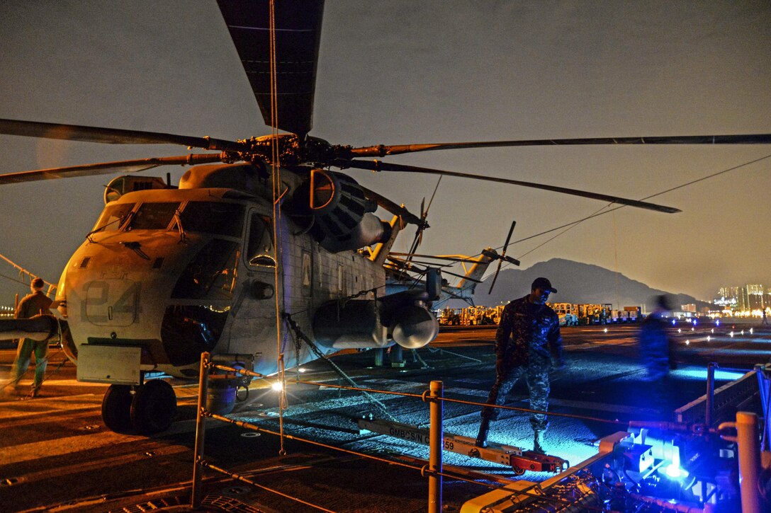 Navy Petty Officer 1st Class Jerome Dunkley stands by as guests look at a display of CH-53E Super Stallions during a friendship reception on the amphibious assault ship USS Bonhomme Richard in Hong Kong, Sept. 29, 2016. The ship is there to experience the city’s rich culture and history as part of a patrol in the region. Navy photo by Petty Officer 2nd Class Sarah Villegas