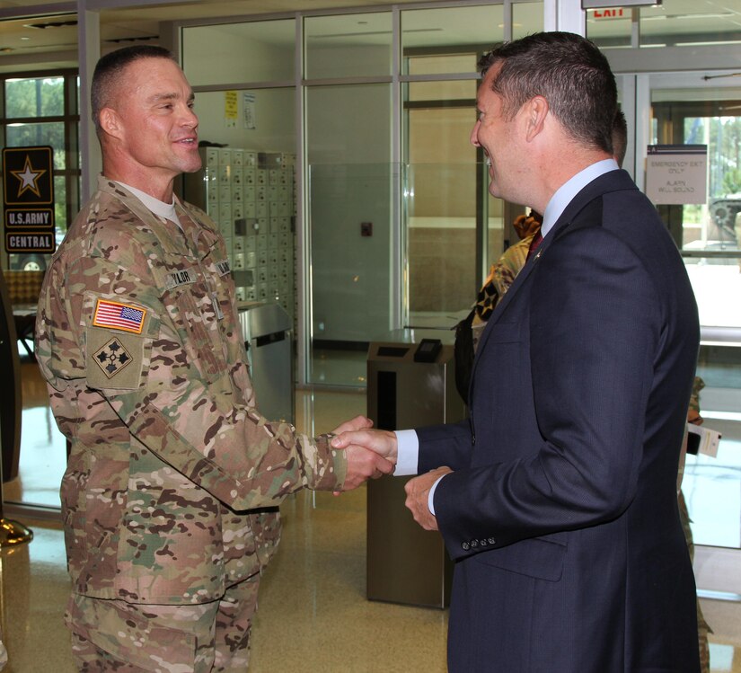 The Honorable Patrick Murphy (right), undersecretary of the Army, gives Maj. James Taylor, an exercise planner assigned to the information operations directorate of U.S. Army Central, a coin for excellence for his entering and winning of an Army body building competition earlier this year. 