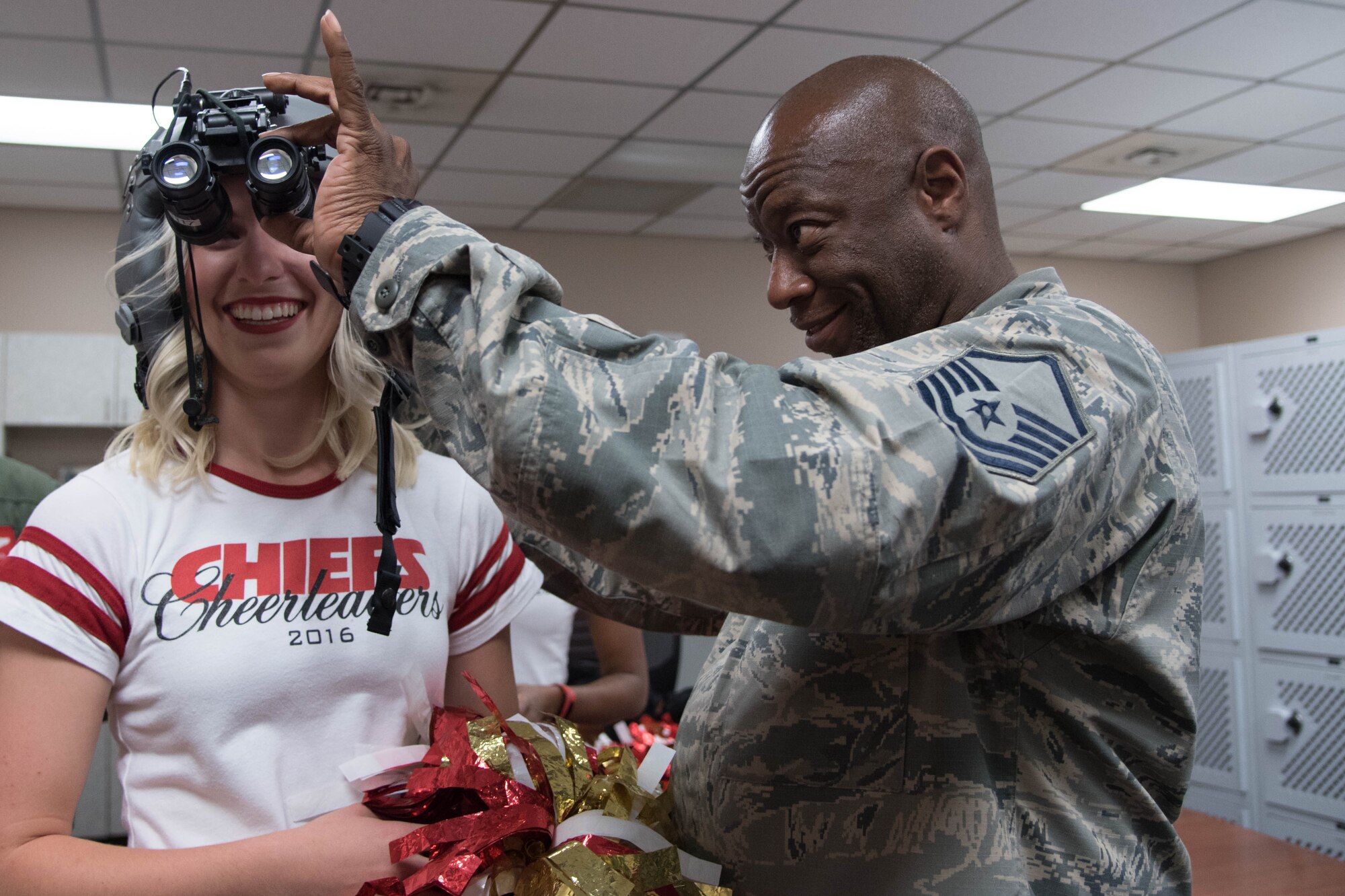 Sarah (team policy dictates that she doesn't share her last name), National Football League cheerleader from the Kansas City Chiefs, tries on night vision goggles with the help of Master Sgt. Ray Reynolds, 815th Airlift Squadron aircrew flight equipment supervisor. The cheerleaders visited Keesler Air Force Base as part of an event hosted by the Army and Air Force Exchange Service that included a tour of the base, a Chiefs’ Cheerleader clinic for children at the Youth Center and a fashion show at the main Exchange. (U.S. Air Force photo/Senior Airman Heather Heiney) 