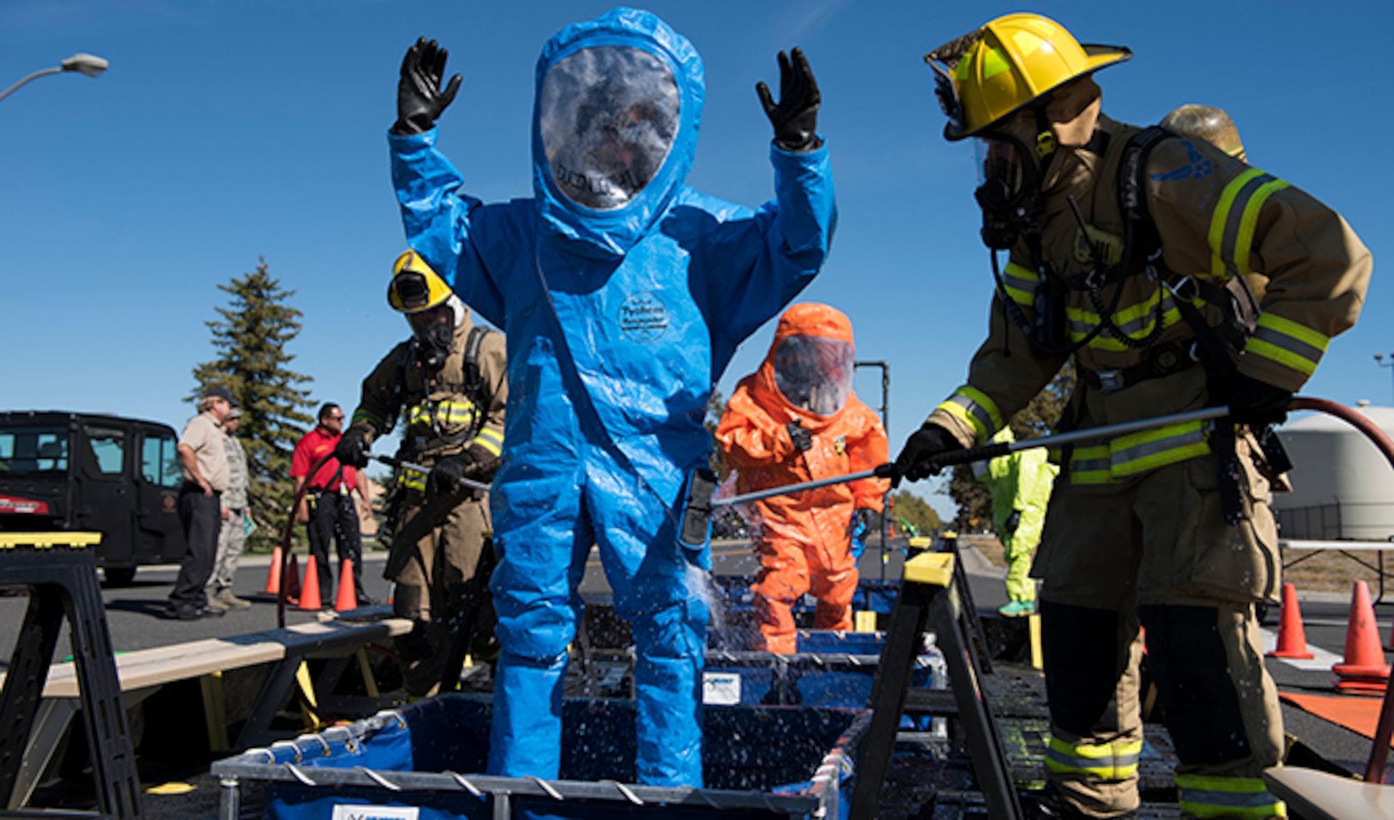 Firefighters from the 92nd Civil Engineer Squadron assist in decontaminating a hazardous materials team’s protective suits after responding to a chemical leak during an Emergency Management Exercise Sept. 29, 2016, at Fairchild Air Force Base, Wash. Exercises allow Airmen to practice vital skills in various formats to keep emergency response abilities sharp in the event of an actual crisis. (U.S. Air Force photo/Airman 1st Class Ryan Lackey)