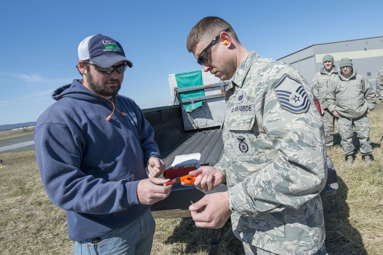 Chad Neil, a wildlife specialist for U.S. Department of Agriculture Animal Plant Health Inspection Service Wildlife Service - West Virginia, assists Master Sgt. Patrick Judy, 167th Airlift Wing Security Forces, with a pyrotechnics pistol as part of a wildlife management course taught at the wing, March 23. Pyrotechnics are one of the tactics used to scare away birds from the airfield for the safety of the aircraft and the animals. (U.S. Air National Guard photo by Senior Master Sgt. Emily Beightol-Deyerle)