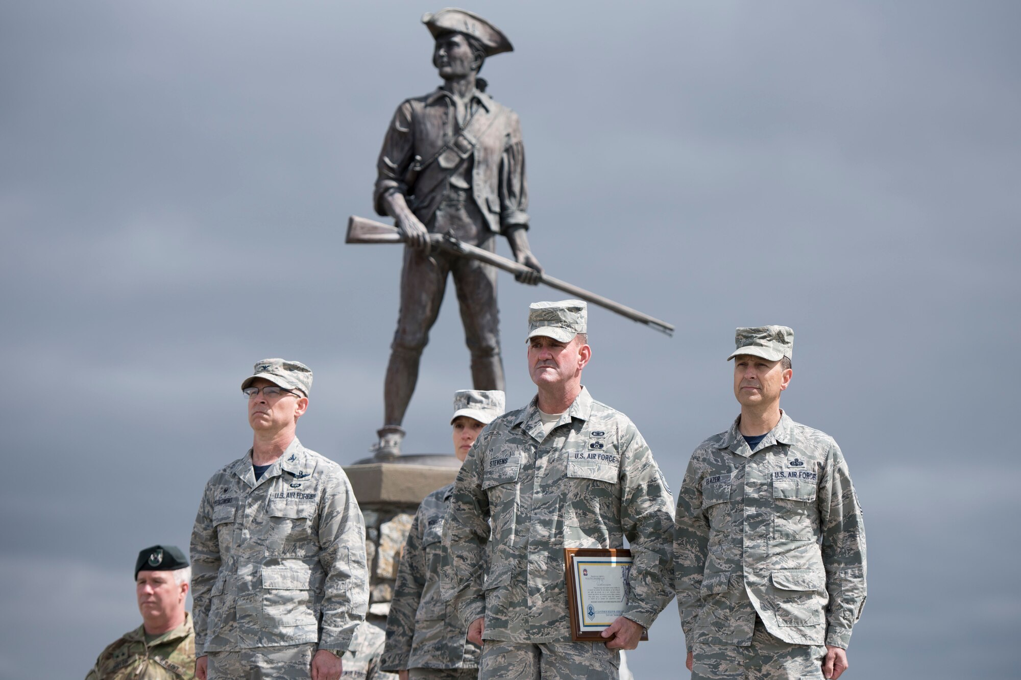 Col. Shaun J. Perkowski, 167th Airlift Wing commander, Chief Master Sgt. David Stevens, incoming wing command chief, and Chief Master Sgt. Ronald R. Glazer, Sr., outgoing command chief, stand at attention during the change of responsibility ceremony held in front of the minuteman statue at the 167th Airlift Wing, April 1. (U.S. Air National Guard photo by Senior Master Sgt. Emily Beightol-Deyerle)