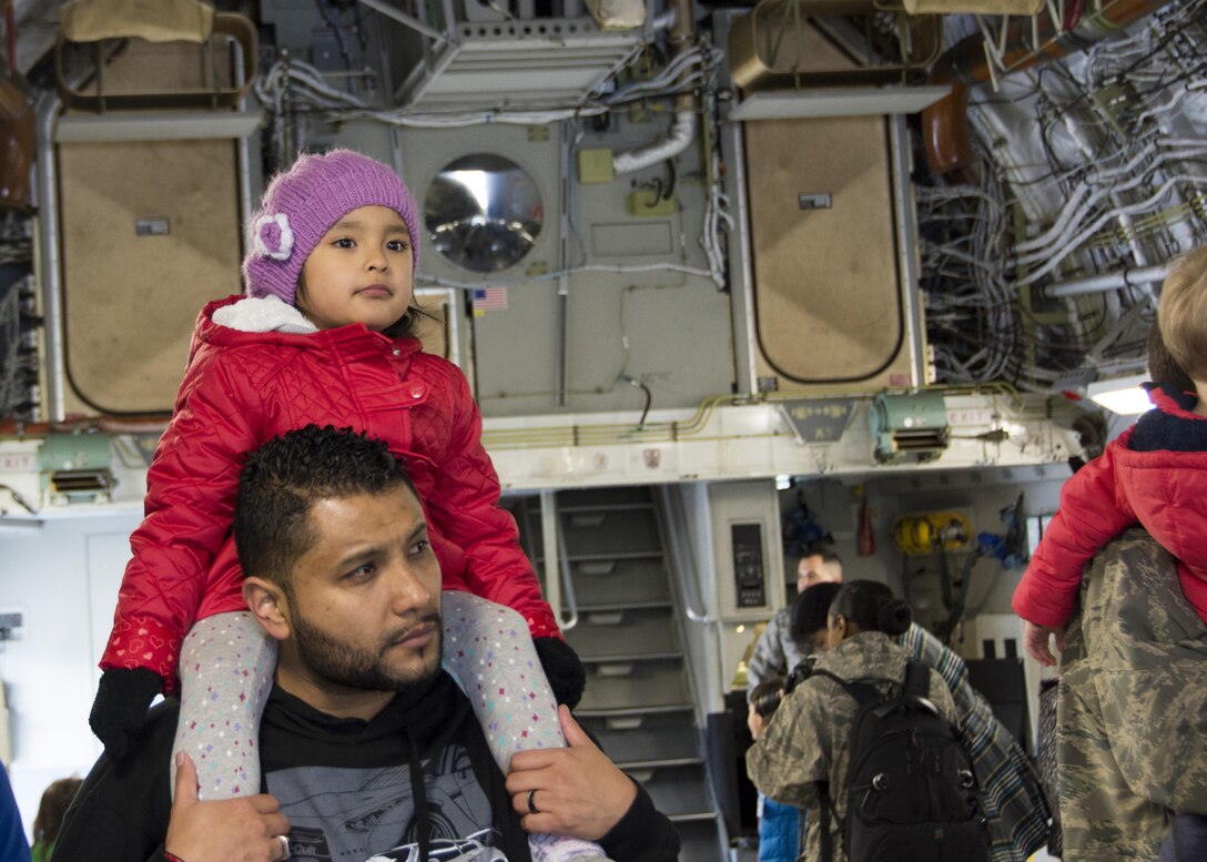 Adelyne Santamaria perches on top of her dad Marco Santamaria’s shoulders as they watch loadmasters from the 512th Airlift Wing demonstrate loading and unloading a C-17 Globemaster III, Dover Air Force Base, Del., April 1, 2017. 512th AW reservists’ family members attended a Month of the Military Child event involving tours of a C-5M Super Galaxy, C-17 Globemaster III, fire station and a demonstration by military working dogs. (U.S. Air Force photo/Staff Sgt. Renee M. Jackson)