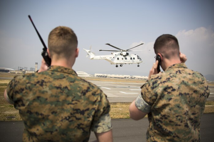 U.S. Marine Corps Lance Cpl. Daniel McGinness, left, and U.S. Marine Corps Cpl. Stephen Wellman, right, air traffic controllers with Headquarters and Headquarters Squadron, guide Japan Maritime Self-Defense Force helicopter pilots onto a designated landing site during a cross-training exercise at Marine Corps Air Station Iwakuni, Japan, March 30, 2017. The Marines took part in a simulated forward arming and refueling points operation, where they communicated with JMSDF helicopter pilots to perform austere landings on a heliport that acted as an expeditionary runway. (U.S. Marine Corps photo by Lance Cpl. Carlos Jimenez)