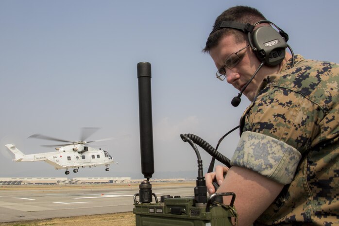 U.S. Marine Corps Cpl. Stephen Wellman, air traffic controller with Headquarters and Headquarters Squadron, guides Japan Maritime Self-Defense Force helicopter pilots onto a designated landing site during a cross-training exercise at Marine Corps Air Station Iwakuni, Japan, March 30, 2017. The Marines took part in a simulated forward arming and refueling points operation, where they communicated with JMSDF helicopter pilots to perform austere landings on a heliport that acted as an expeditionary runway. (U.S. Marine Corps photo by Lance Cpl. Carlos Jimenez)