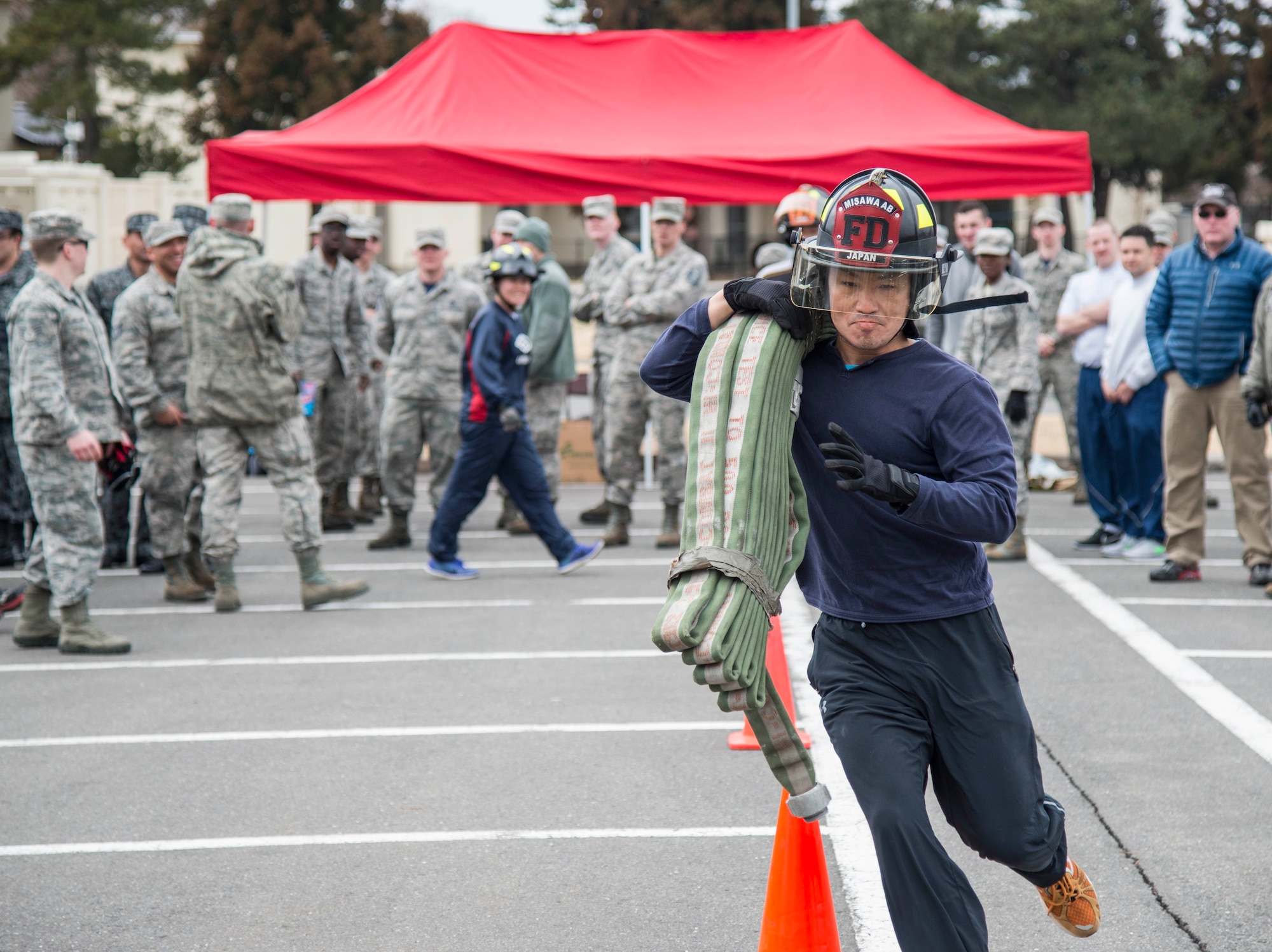 A Japanese National runs with a fire hose during Wingman Day at Misawa Air Base, Japan, March 31, 2017. During the firetruck pull event, teams had to complete three stations, which included a body drag, hose run and a firetruck pull. (U.S. Air Force Senior Airmen Brittany A. Chase)