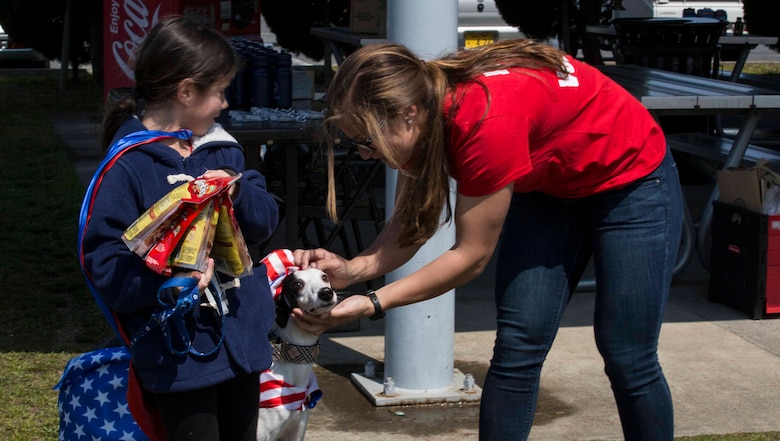 U.S. Marine Corps 2nd Lt. Scotti Culton pets the second-place winner of the dog-costume contest during the Active-Duty Fund Drive Dog Parade at Marine Corps Air Station Iwakuni, Japan, April 1, 2017. The Navy-Marine Corps Relief Society held the event to bring the community together and increased awareness of its fund drive. Eleven dog owners registered for the event and walked from Penny Lake to the harbor gate and back. They also participated in a dog-costume contest. (U.S. Marine Corps photo by Lance Cpl. Gabriela Garcia-Herrera)