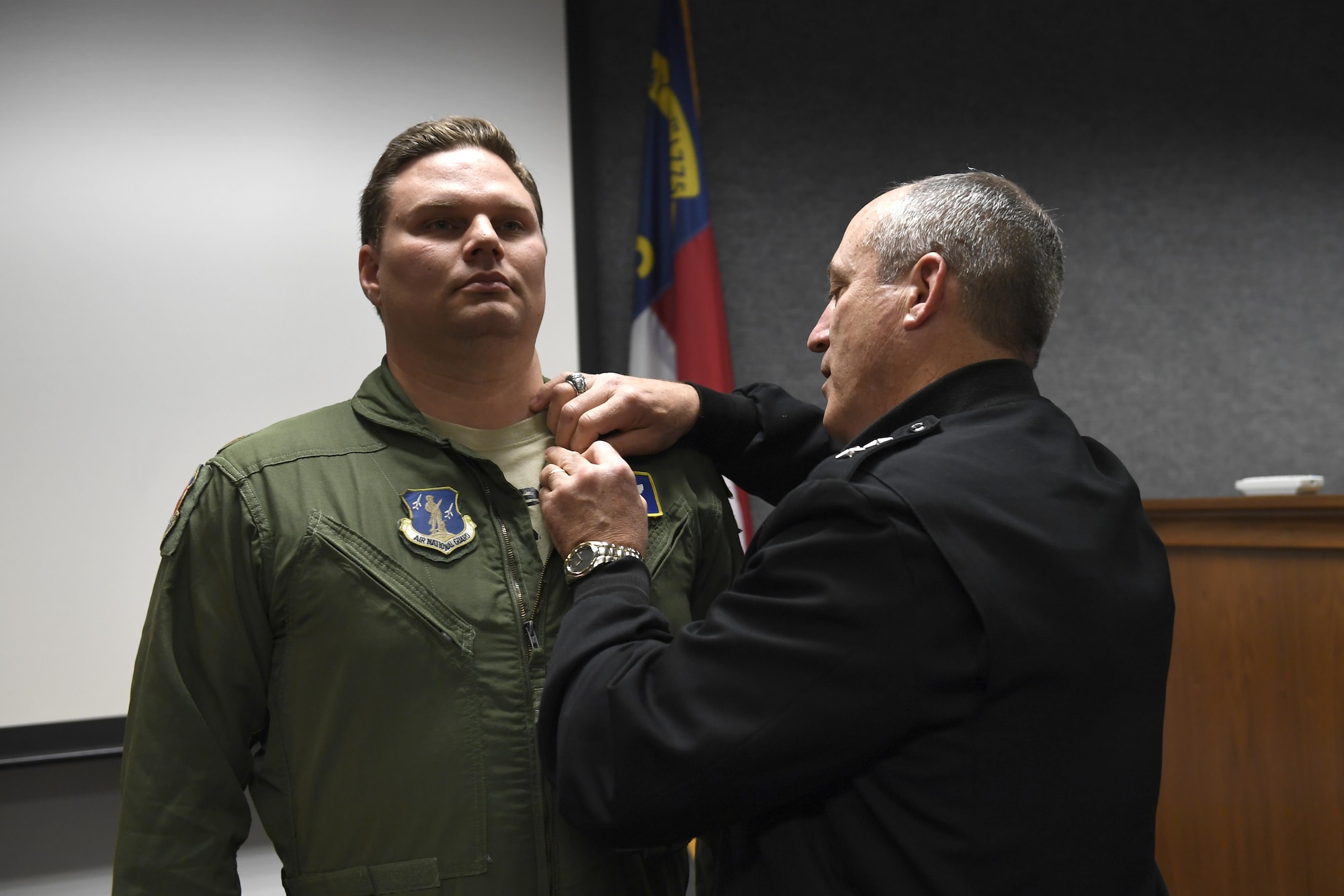 U.S. Army Maj. Gen. Greg Lusk (center), the Adjutant General of North Carolina, commander of the North Carolina National Guard, pins the North Carolina National Guard Soldier and Airman Medal for heroism onto U.S. Air Force Maj. Nathan Barron (left), 156th Airlift Wing, during a ceremony held at the North Carolina Air National Guard Base, Charlotte Douglas International Airport, April 1, 2017. Barron acted decisively and courageously by tackling and maneuvering an unruly passenger to the ground after he assaulted a flight attendant. Barron continued to subdue the passenger until law enforcement arrived which saved the lives of the crew as well as others aboard the plane. The medal was recently created to honor Soldiers and Airmen for heroic actions performed while out of the military uniform.
