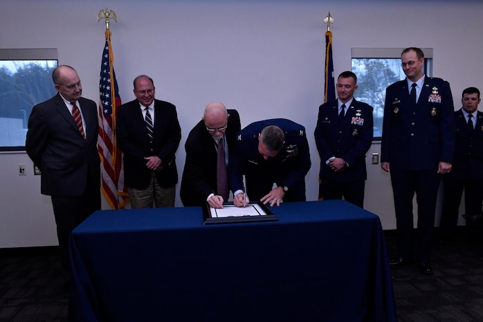 Col. Rob Lyman, right, Joint Base Charleston commander, signs a memorandum of agreement with Keith Bustraan, Charleston County administrator, at the Charleston County Consolidated 911 Center, March 30, 2017. The Enhanced 911 initiative combines the call centers for the 628th Security Forces Squadron and fire department with the Charleston County Consolidated 911 Center, ultimately shortening response times, saving money and saving lives.