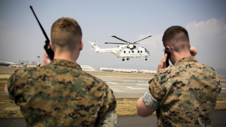 U.S. Marine Corps Lance Cpl. Daniel McGinness, left, and U.S. Marine Corps Cpl. Stephen Wellman, right, air traffic controllers with Headquarters and Headquarters Squadron, guide Japan Maritime Self-Defense Force helicopter pilots onto a designated landing site during a cross-training exercise at Marine Corps Air Station Iwakuni, Japan, March 30, 2017. The Marines took part in a simulated forward arming and refueling points operation, where they communicated with JMSDF helicopter pilots to perform austere landings on a heliport that acted as an expeditionary runway. 