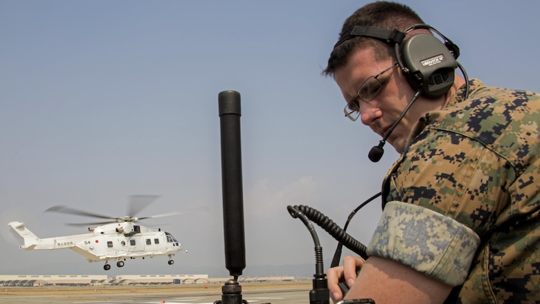 U.S. Marine Corps Cpl. Stephen Wellman, air traffic controller with Headquarters and Headquarters Squadron, guides Japan Maritime Self-Defense Force helicopter pilots onto a designated landing site during a cross-training exercise at Marine Corps Air Station Iwakuni, Japan, March 30, 2017. The Marines took part in a simulated forward arming and refueling points operation, where they communicated with JMSDF helicopter pilots to perform austere landings on a heliport that acted as an expeditionary runway.