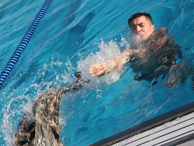 A U.S. Army Soldier tosses part of his uniform from the pool following the 100-meter swim during the German Armed Forces Badge testing at the Fort Sam Houston Aquatics Center at Joint Base San Antonio-Fort Sam Houston March 31. Competitors needed to complete the swim in four minutes or less before treading water and removing their uniform.