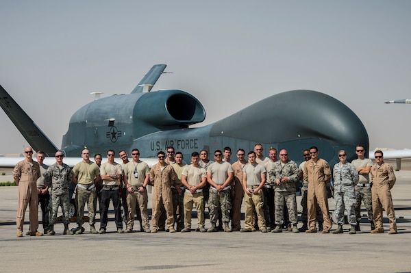 Members of the 380th Expeditionary Aircraft Maintenance Squadron and the 99th Expeditionary Reconnaissance Squadron pose for a group photo after successfully completing 1000 consecutive sorties without a maintenance cancel in support of Combined Joint Task Force-Operation Inherent Resolve at an undisclosed location, April 1, 2017. These remotely piloted aircraft have provided a critical communication bridge between multi-national Coalition assets working to defeat ISIS in the area of responsibility. (U.S. Air Force/Senior Airman Tyler Woodward)