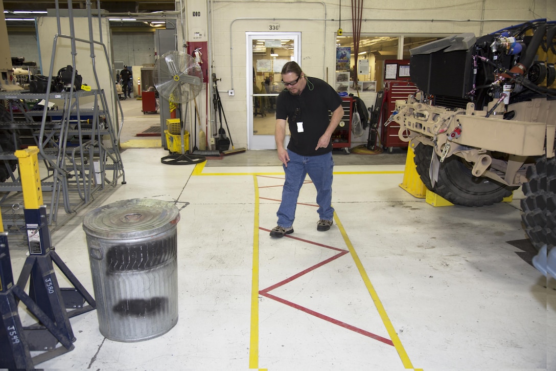 Ted Fisher points out the clear access pathway created by the Safety Office to allow easy entrance and exit from the door behind him. March 9. Prior to the establishment of the pathway, crates and equipment would accumulate in front of the door creating a potentially dangerous situation. Fisher is the supervisor of the Safety Office at Production Plant Barstow, Marine Depot Maintenance Command, aboard the Yermo Annex of Marine Corps Logistics Base Barstow, Calif.