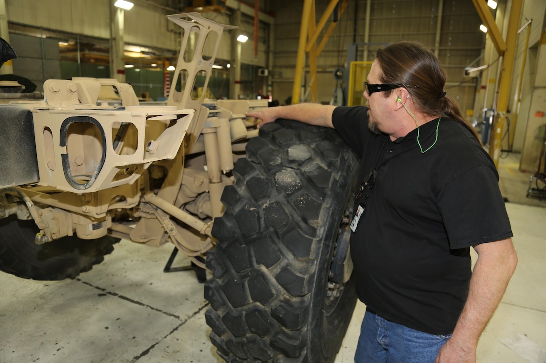Ted Fisher explains that the Safety Office crew is trying to design a better way to change parts of the suspension on a Logistics Vehicle System Replacement truck. The artisans at Production Plant Barstow are following the way the maintenance manual recommends, but Fisher said the procedure is not as safe as it could be.