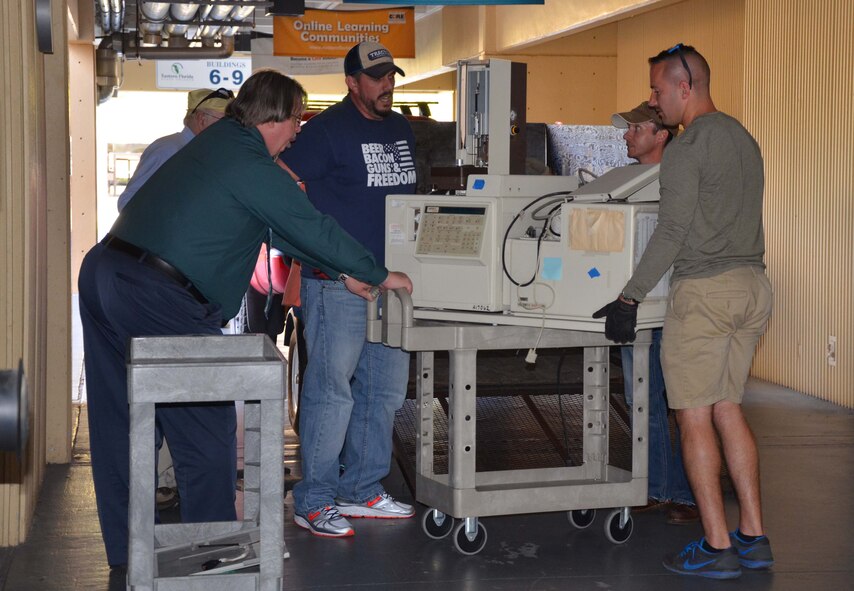 Dr. Dan Mackney, a senior chemist with the Air Force Technical Applications Center, Patrick AFB, Fla., gives directions to his co-workers as they download mass spectrometry equipment from a truck onto a mobile trolley to position it in a science lab at Eastern Florida State College March 17, 2017.  The school requested Mackney’s expertise and help with setting up the donated equipment.  Pictured from left to right:  Mackney, Bart Scarbro, Dr. Richard Reich and Pete Oliveri.  (U.S. Air Force photo by Susan A. Romano)