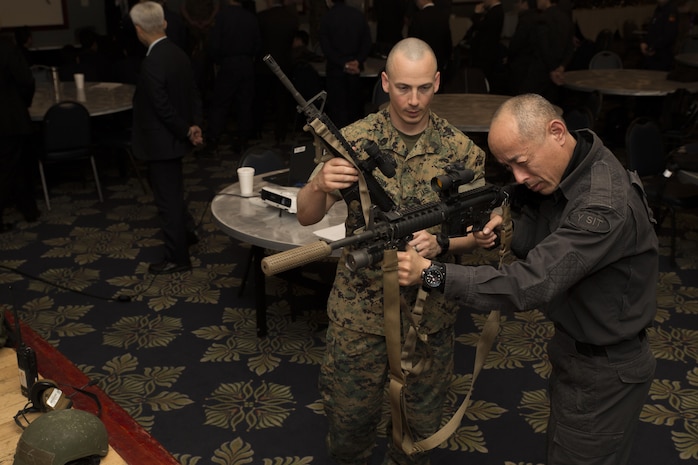 U.S. Marine Corps Gunnery Sgt. Freddie Herrin, left, the Special Reaction Team (SRT) commander for Marine Corps Air Station (MCAS) Iwakuni, shows weapons used by SRT to a member of the Yamaguchi Prefectural Police Headquarters, right, at MCAS Iwakuni, Japan, March 28, 2017. Members with the Hiroshima and Yamaguchi Prefectural Police Headquarters traveled to the air station to observe SRT conduct high-risk training scenarios. The training ranged from room-clearing, breaching, communication and non-lethal take-down techniques.