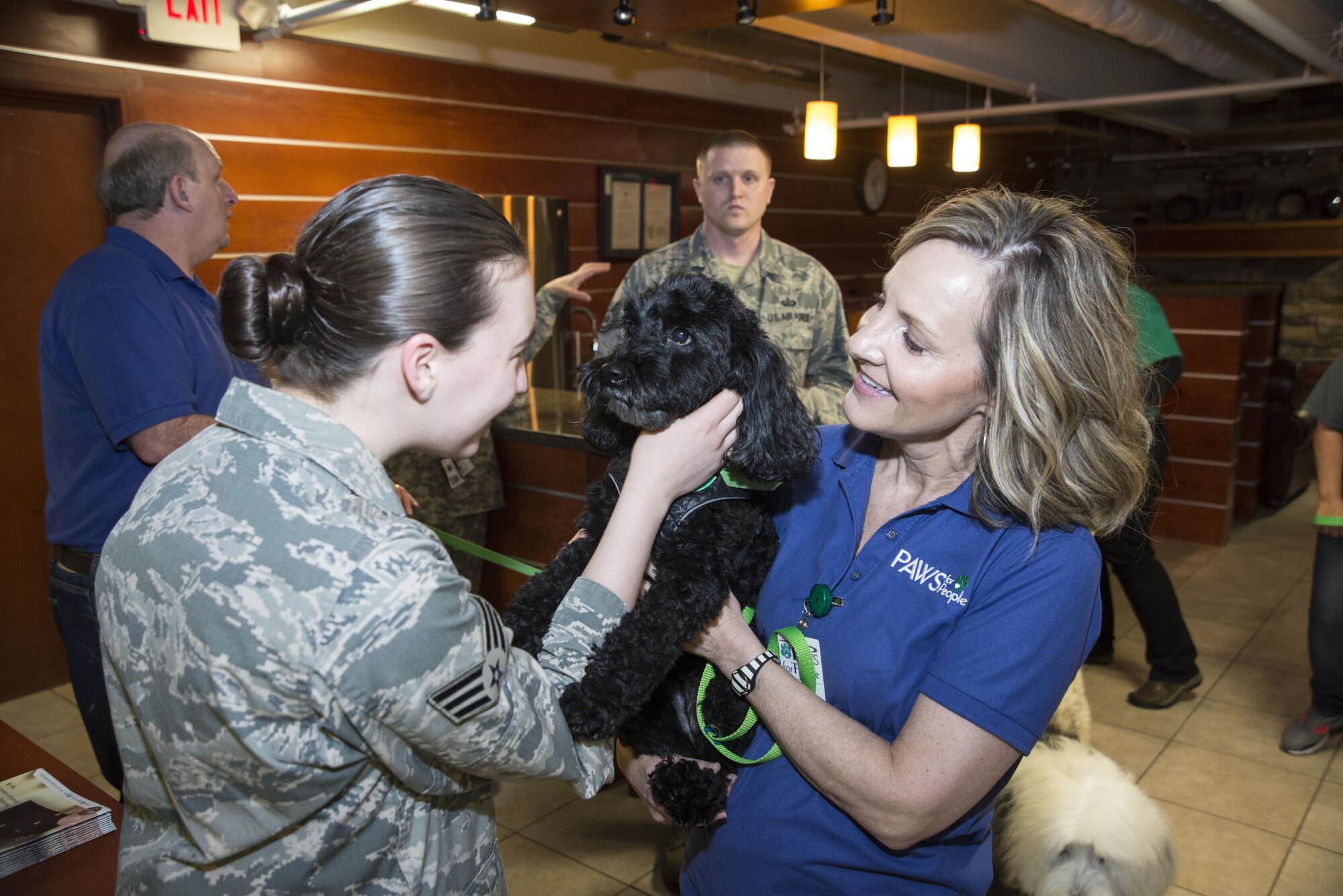Senior Airman Sarah Cruz, Air Force Mortuary Affairs Operations personal effect s specialist, pets “Tilly,” a PAWS for People dog, during a visit from PAWS for People, March 28, 2017, at AFMAO on Dover Air Force Base, Del. “Tilly” and her owner, Tammy Tatoian, are a part of a program which provides therapeutic visits with a well-trained, loving pet to different organizations and groups. (U.S. Air Force photo by Staff Sgt. Jared Duhon)