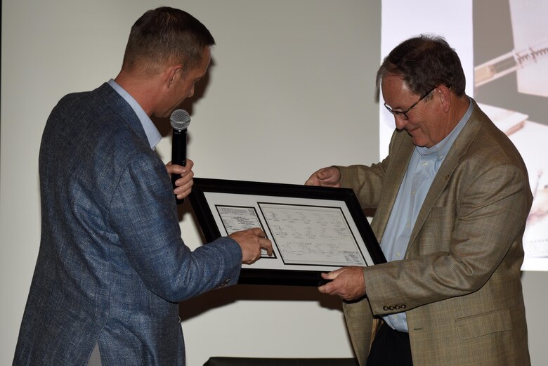 Col. James DeLapp (Left), former U.S. Army Corps of Engineers Nashville District commander and current commander of the Mobile District, presents Mike Wilson, deputy district engineer for Project Management, with a blueprint for the monolith that he designed at Bay Springs Lock on the Tennessee Tombigbee Waterway during a social event in Nashville, Tenn., March 31, 2017. The blueprint included Wilson's initials signed Aug. 12, 1981, a keepsake honoring Wilson on the day of his retirement after nearly 42 years of federal service.