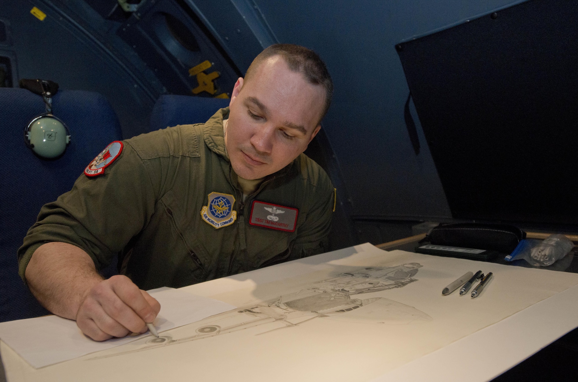 Tech Sgt. Timothy McCarthy, 22nd Airlift Squadron, adds details to a drawing he plans to give to an individual leaving, during some down time on a recent mission to Japan March 3, 2017. McCarthy is a self taught artist who has done drawings and painting throughtout the squadron as well as for going away presents when he's not doing flight engineer duties. (U.S. Air Force photo/Staff Sgt. Nicole Leidholm)